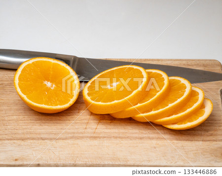 A knife is on a cutting board with a sliced orange A knife is on a cutting board with a sliced orange 133446886
