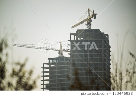 Two cranes are in the background of a building 133446928