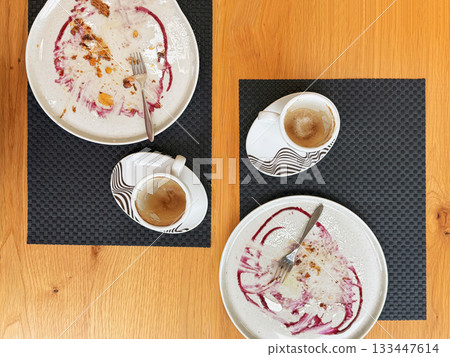 Two coffee cups with empty dessert plates on wooden table, showing remnants of Thanksgiving pumpkin strudel. Concept of shared autumn moment over sweet pastries and cozy seasonal drinks Two coffee cups with empty dessert plates on wooden table, showing remnants of Thanksgiving pumpkin strudel. Concept of shared autumn moment over sweet pastries and cozy seasonal drinks 133447614