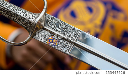 This close view showcases a ceremonial Sikh Kirpan featuring a polished steel blade and an intricately designed silver hilt, reflecting cultural significance and artistry. 133447626