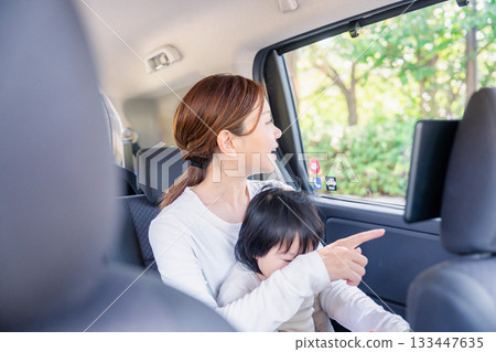 一位母親帶著孩子坐在計程車裡，望著窗外。 133447635