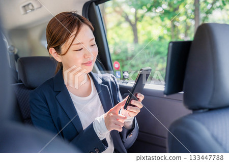A young female business person using a smartphone in a taxi 133447788