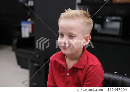 Blond boy smiling receiving fresh haircut in barbershop 133447994