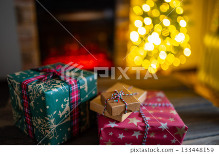 Cozy Christmas Interior with Fireplace, Gift Boxes, and Decorated Tree with Warm Lights 133448159
