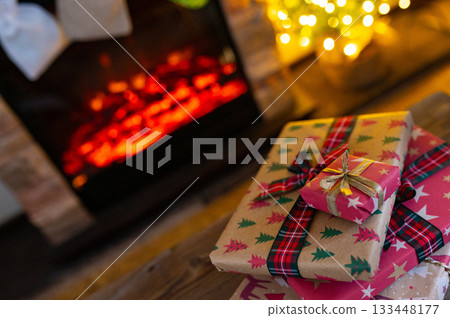 Cozy Christmas Interior with Fireplace, Gift Boxes, and Decorated Tree with Warm Lights 133448177
