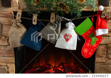 Advent Calendar Bags and Christmas Stockings Hanging Above Cozy Fireplace Advent Calendar Bags and Christmas Stockings Hanging Above Cozy Fireplace 133448227