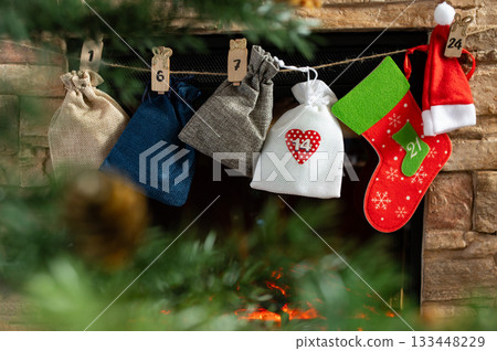Advent Calendar Bags and Christmas Stockings Hanging Above Cozy Fireplace Advent Calendar Bags and Christmas Stockings Hanging Above Cozy Fireplace 133448229