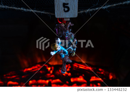 Krampus Ornament Carrying Child Hanging on Advent Garland Above Fireplace 133448232