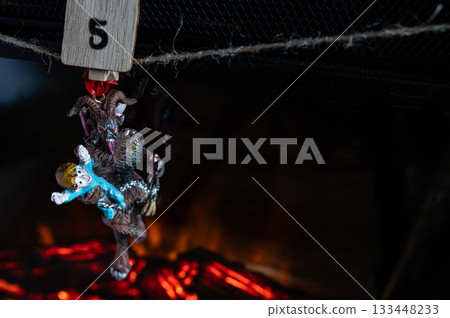 Krampus Ornament Carrying Child Hanging on Advent Garland Above Fireplace 133448233