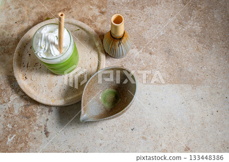 Matcha latte glass, matcha bowl, a bamboo whisk Chasen on travertine tray 133448386