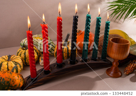 Happy Kwanzaa. Seven candles red, black and green on a natural wooden background. Harvest and gifts. Symbols of African heritage. Happy Kwanzaa. Seven candles red, black and green on a natural wooden background. Harvest and gifts. Symbols of African heritage. 133448452
