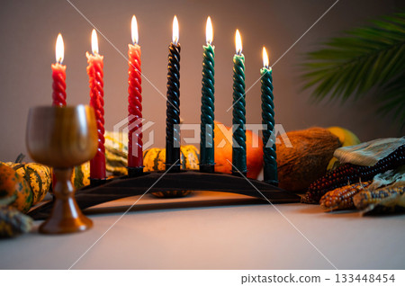 Happy Kwanzaa. Seven candles red, black and green on a natural wooden background. Harvest and gifts. Symbols of African heritage. 133448454