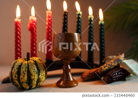 Happy Kwanzaa. Seven candles red, black and green on a natural wooden background. Harvest and gifts. Symbols of African heritage. 133448460