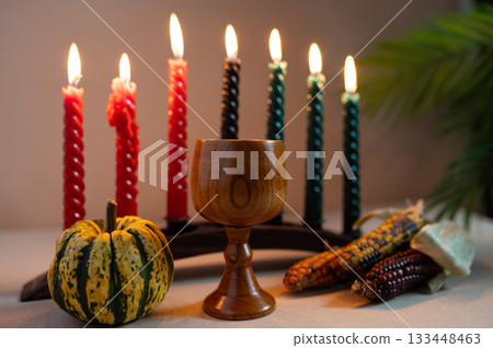 Happy Kwanzaa. Seven candles red, black and green on a natural wooden background. Harvest and gifts. Symbols of African heritage. 133448463