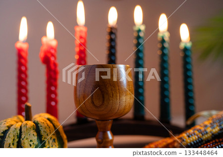Happy Kwanzaa. Seven candles red, black and green on a natural wooden background. Harvest and gifts. Symbols of African heritage. 133448464