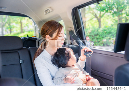 Mother with child fastening seat belt in taxi 133448641