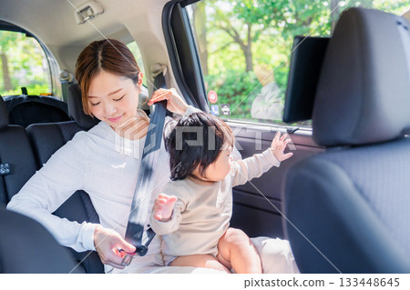 Mother with child fastening seat belt in taxi 133448645