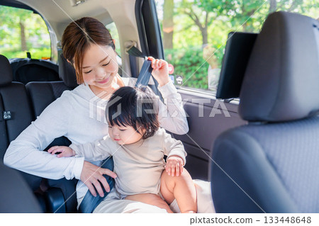 Mother with child fastening seat belt in taxi Mother with child fastening seat belt in taxi 133448648