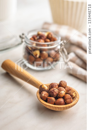 Peeled hazelnut kernels on wooden spoon on kitchen table. Peeled hazelnut kernels on wooden spoon on kitchen table. 133448718