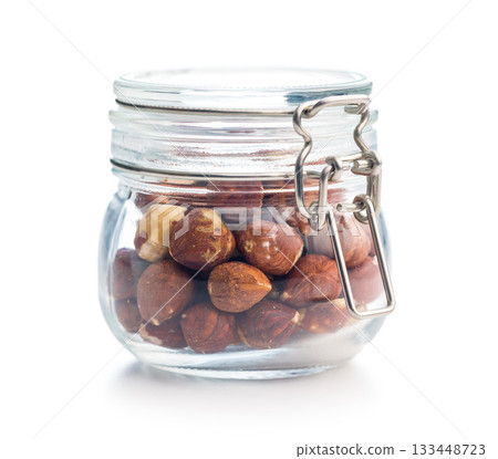 Peeled hazelnut kernels in jar isolated on white background. Peeled hazelnut kernels in jar isolated on white background. 133448723