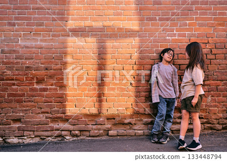 Asian children having conversation on brick wall 133448794