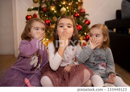Friends sharing a playful moment near the festive Christmas tree 133449123