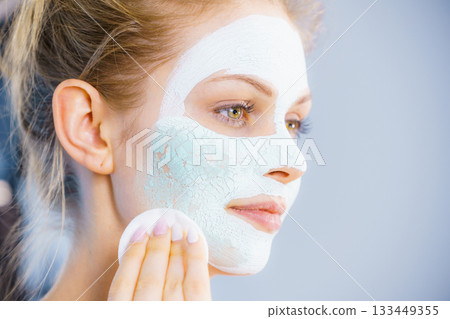Girl removes dry white mud mask Girl removes dry white mud mask 133449355