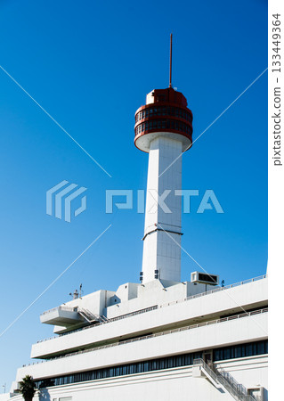 The Ship Science Museum building with its white walls and orange observation deck under the bright blue sky and dazzling sunlight 133449364