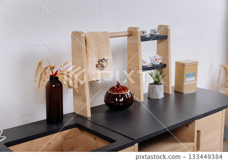 Close up of wooden toy kitchen countertop with towel rack and miniature tea set Close up of wooden toy kitchen countertop with towel rack and miniature tea set 133449384