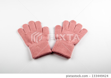 A pair of pink knitted wool gloves on a white background. Warmth, comfort and cozy winter clothing 133449424