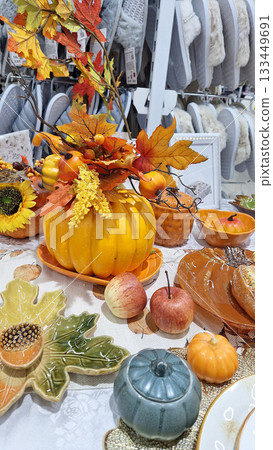 Autumn-themed decorative table display featuring pumpkins, leaves, and seasonal fruits 133449691
