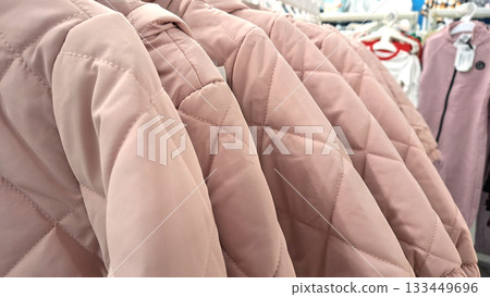 Russia, Moscow- 6 November 2025.Close-up of a quilted pink jacket with neat stitching displayed on a retail clothing rack 133449696