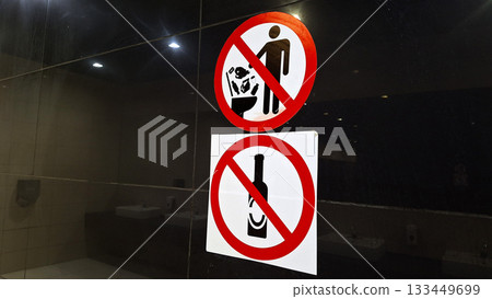 Restroom prohibition signs indicating no disposal of waste or bottles in toilets 133449699