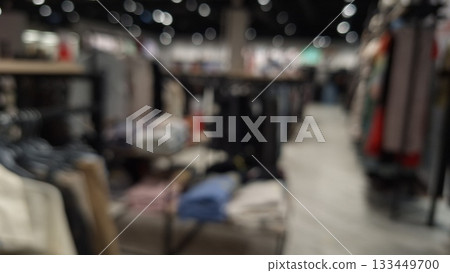 Blurred indoor market scene showcasing a variety of clothing and textile stalls under bright lights Blurred indoor market scene showcasing a variety of clothing and textile stalls under bright lights 133449700