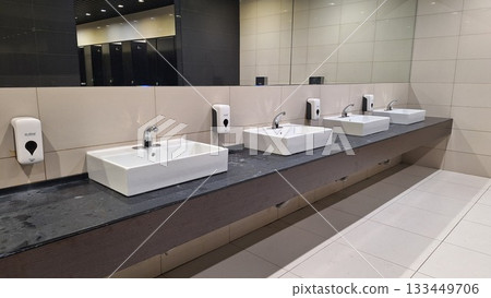 Russia, Moscow- 22 October 2025.Modern public restroom featuring sleek sinks, soap dispensers, and a clean, minimalist design 133449706