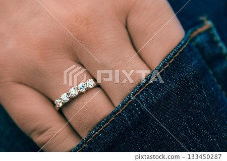 A person is wearing a gold ring with diamonds on it 133450287