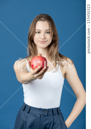 Beautiful woman giving red pomegranate fruit to camera Beautiful woman giving red pomegranate fruit to camera 133450323