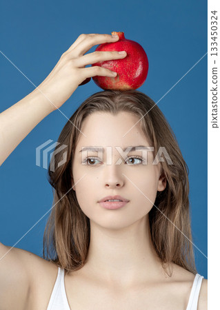 Beautiful young woman holding pomegranate fruit on her head Beautiful young woman holding pomegranate fruit on her head 133450324