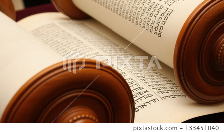 A close-up view of an open Torah scroll, revealing ancient Hebrew script on parchment. This image conveys a sense of sacred tradition, history, and faith. Perfect for religious content. 133451040