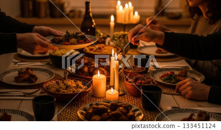 People sharing a festive meal at a table illuminated by candlelight. This intimate scene evokes warmth, togetherness, and tradition. Perfect for holiday, family, or food-related themes. People sharing a festive meal at a table illuminated by candlelight. This intimate scene evokes warmth, togetherness, and tradition. Perfect for holiday, family, or food-related themes. 133451124