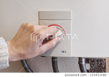Hands set the temperature of the water in the gas boiler Hands set the temperature of the water in the gas boiler 133451480