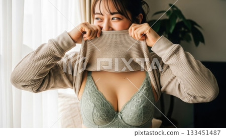 一名身穿淺綠色內衣的女子站在窗邊，裙子撩到嘴邊，臉上帶著幸福的笑容。 133451487