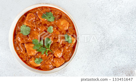Indian butter chicken curry in a white bowl with fresh cilantro on white background. Top view. Copy space. Banner 133451647