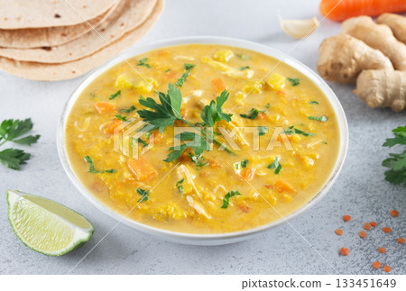 Bowl of Mulligatawny soup with fresh vegetables, lime, herbs and roti bread. Traditional Indian dish. 133451649