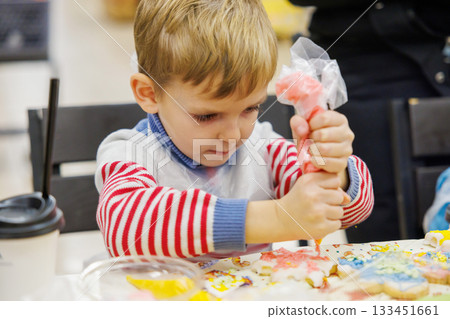Child Decorating Cookies with Icing at a Creative Workshop Child Decorating Cookies with Icing at a Creative Workshop 133451661