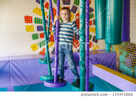 Child Enjoying Indoor Playground Adventure on Colorful Equipment 133451668
