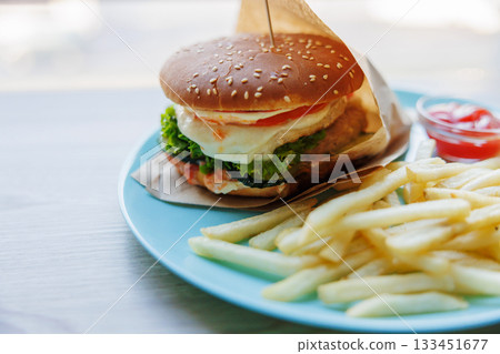Delicious Cheeseburger with Fries on a Blue Plate 133451677