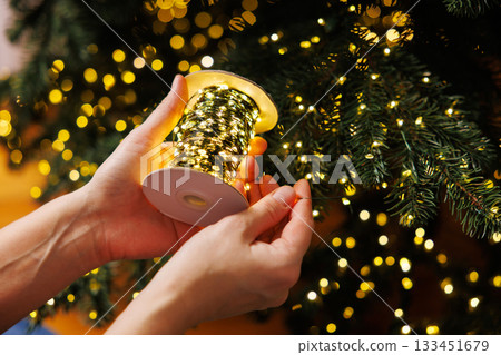 Hands Decorating Christmas Tree with String Lights Hands Decorating Christmas Tree with String Lights 133451679