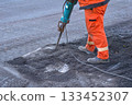 Repair.A road worker breaks up old asphalt with a jackhammer 133452307
