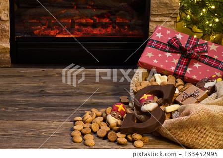 Festive St. Nicholas Scene. Cozy holiday setting with a fireplace, gifts Festive St. Nicholas Scene. Cozy holiday setting with a fireplace, gifts 133452995